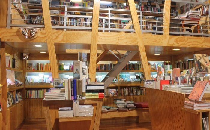 Fotografía de una de las Librerías UC por dentro, se ven muchas vigas de madera y estantes, con cientos de libros