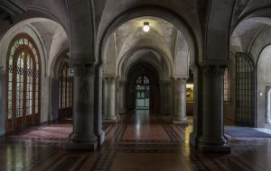 Fotografía del hall del Campus Oriente UC, se ven varios pasillos hechos por gruesas columnas de piedra