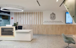 Fotografía de la Escuela de Administración Pública UC por dentro, se ve un mesón y el nombre de la Escuela al fondo