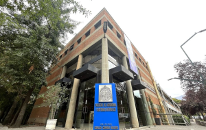 Fotografía del frontis de la Facultad de Agronomía y Sistemas Naturales UC, en frente se ve un cartel con el nombre de la Facultad