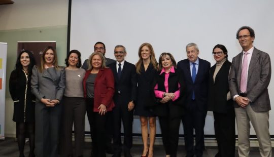 Fotografía de once personas posando en una sala durante un evento institucional.