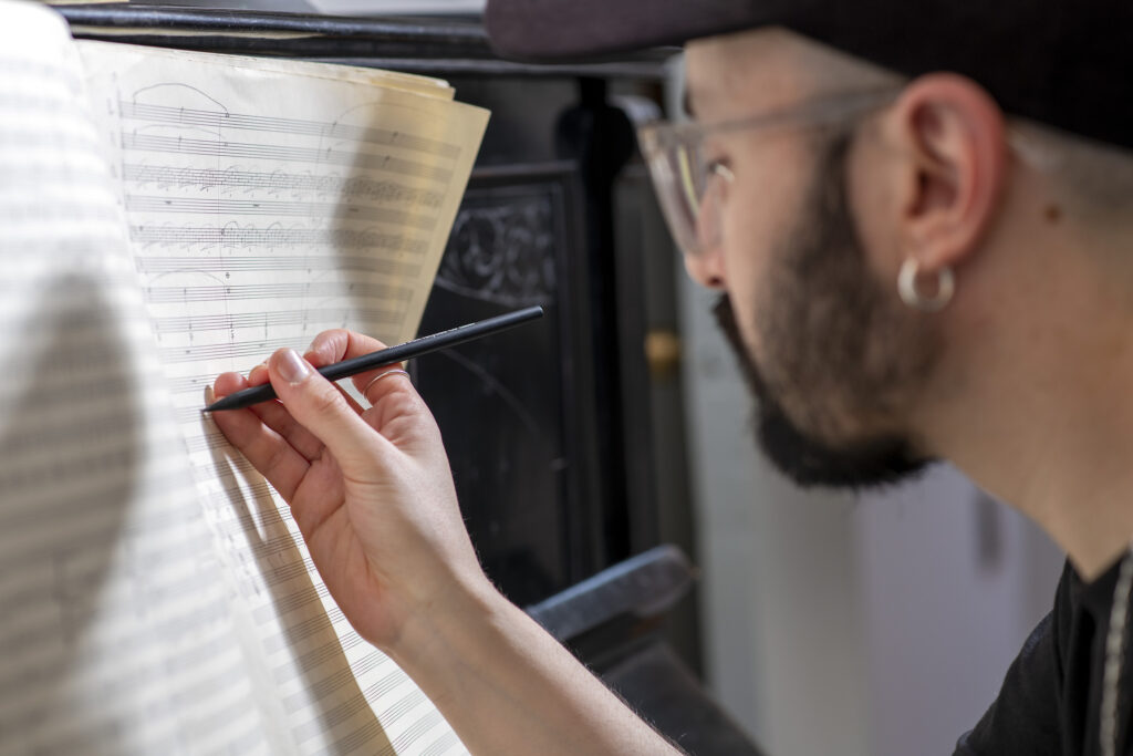 Fotografía del perfil de Tomás Brantmayer escribiendo sobre una partitura.