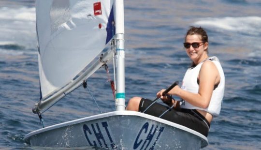 Fotografía de la Alumni UC, María José Poncell sonriendo mientras practica vela