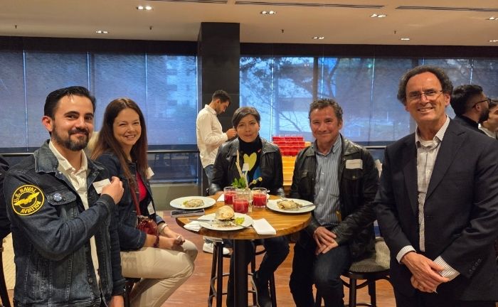 Fotografía del Rector UC, Juan Carlos de la Llera, junto a exalumnos en Colombia sonriendo y compartiendo un cóctel