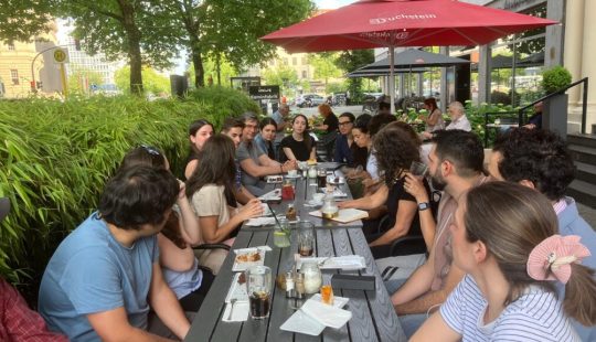 Grupo de personas sentadas alrededor de una mesa en una terraza.