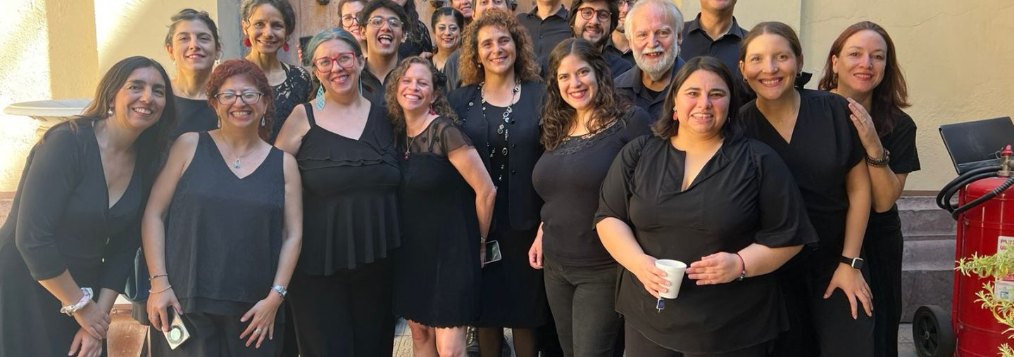 Fotografía de un grupo coral, se ven vestidos de negro y sonriendo