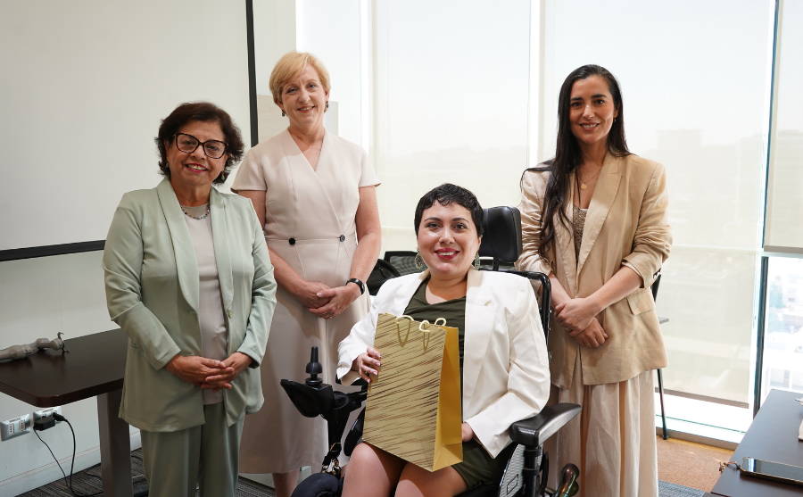 Mujer usuaria de silla de ruedas sosteniendo un regalo junto a otras tres mujeres
