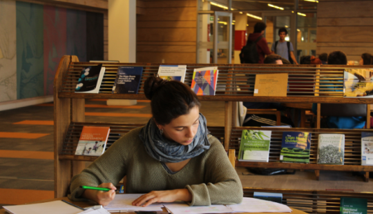 Fotografía de una persona estudiando en una biblioteca